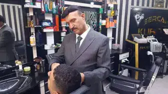 MESLEĞİNE AŞIK BERBER MÜŞTERİLERİNİ TAIM ELBİSE İLE TRAŞ EDİYOR!