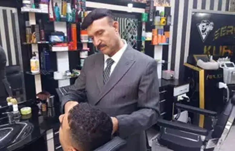 MESLEĞİNE AŞIK BERBER MÜŞTERİLERİNİ TAIM ELBİSE İLE TRAŞ EDİYOR!